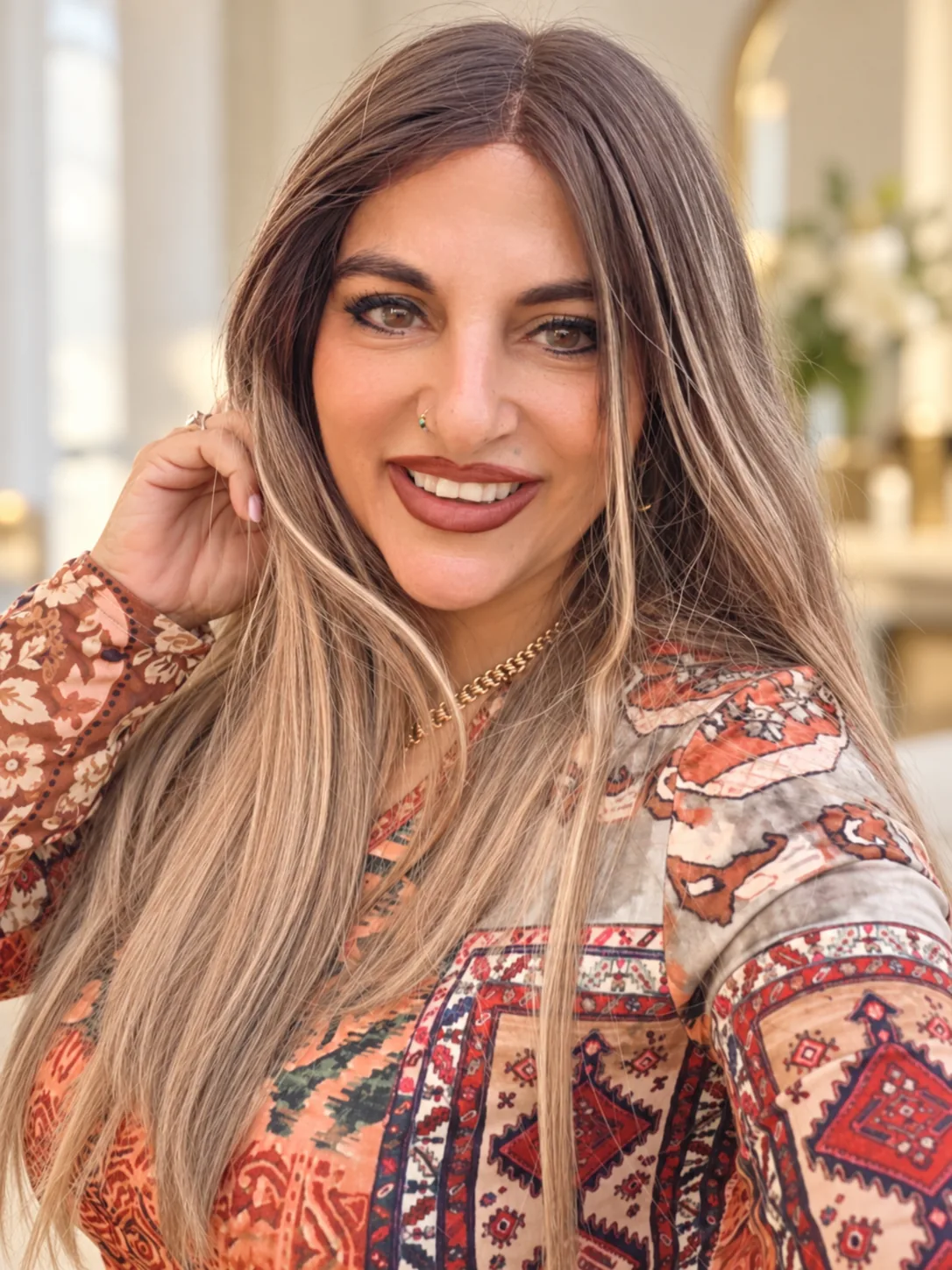 טליה צעידי מחייכת למצלמה, שיער ארוך בגוונים חמים, באור רך של הסטודיו