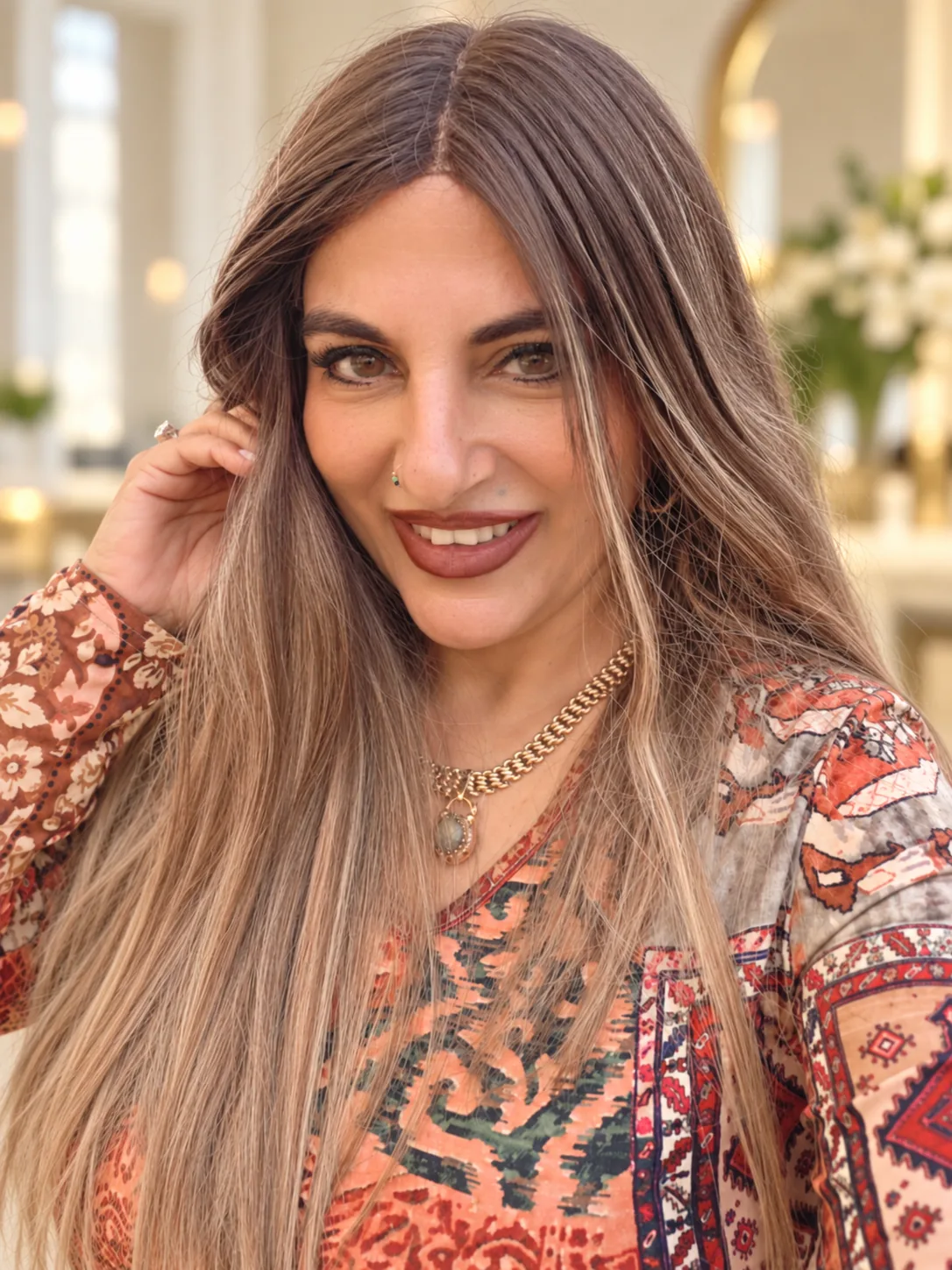 טליה צעידי מחייכת, שיערה הארוך בגוונים חמים, בסטודיו